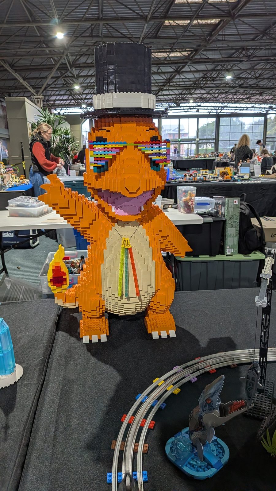 A large orange brick-built Charmander wearing a top hat and rainbow glasses