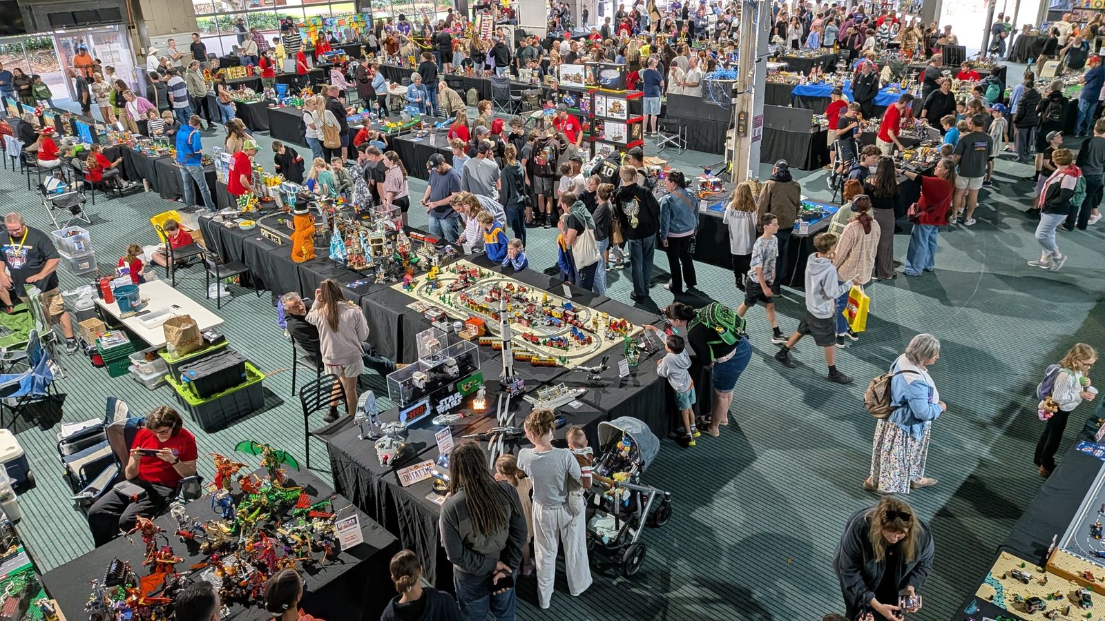 Crowds of visitors exploring rows of LEGO display tables at Newcastle Racecourse