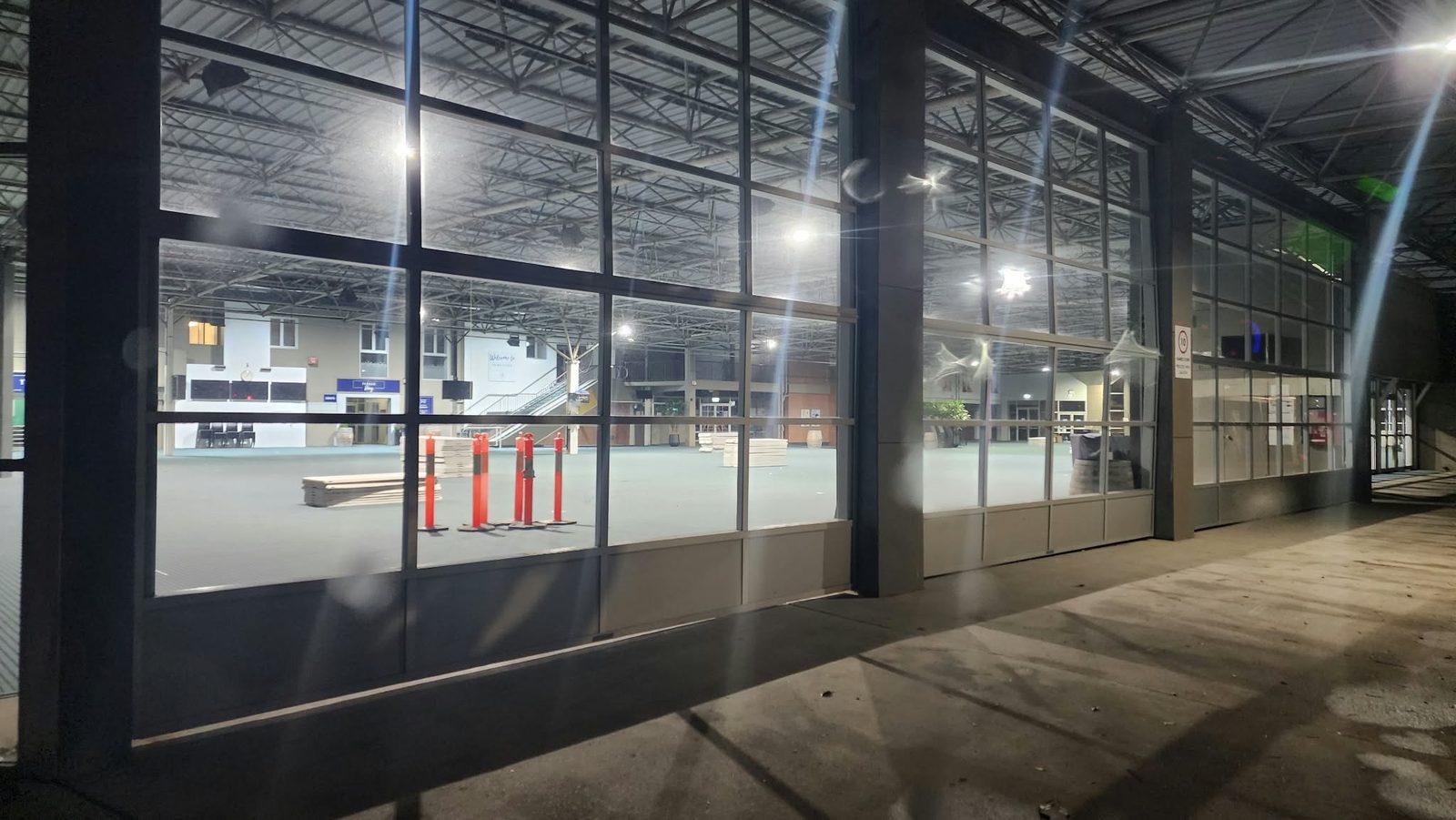 The empty, brightly lit hall seen through glass doors at night