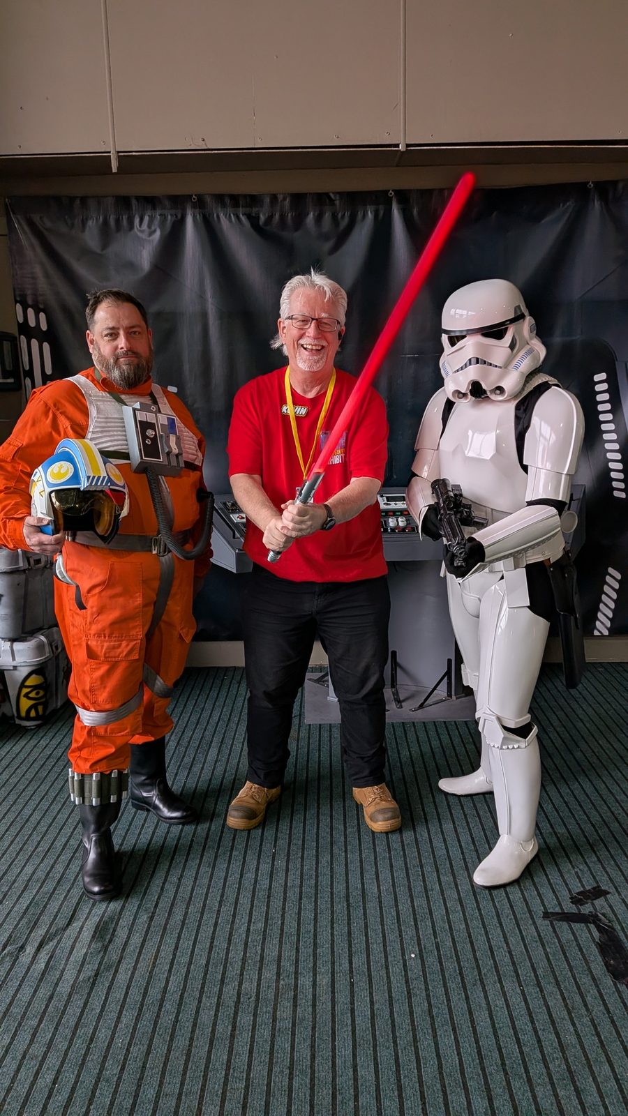 Kevin with a red lightsaber, flanked by an X-wing pilot and a stormtrooper